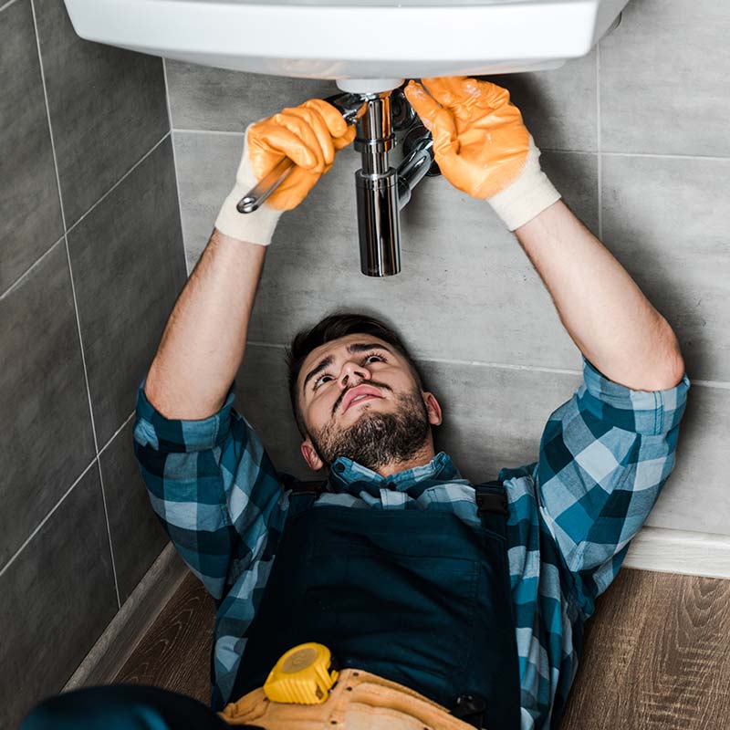 A plumber fixing a sink in a bathroom.