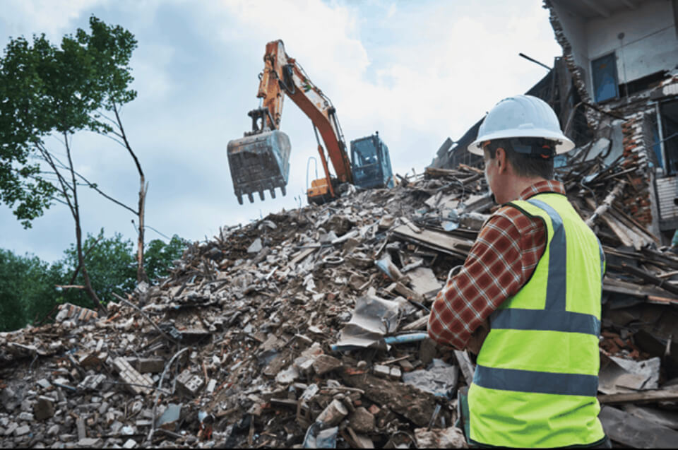 A man is standing in front of a pile of rubble.
